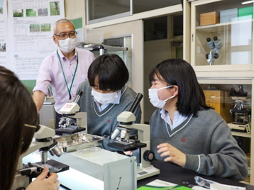 中垣教授に質問しながら顕微鏡を覗く高校生たち